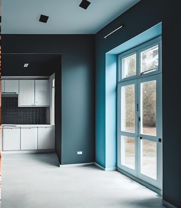 After: finished apartment with dark teal walls and white kitchen